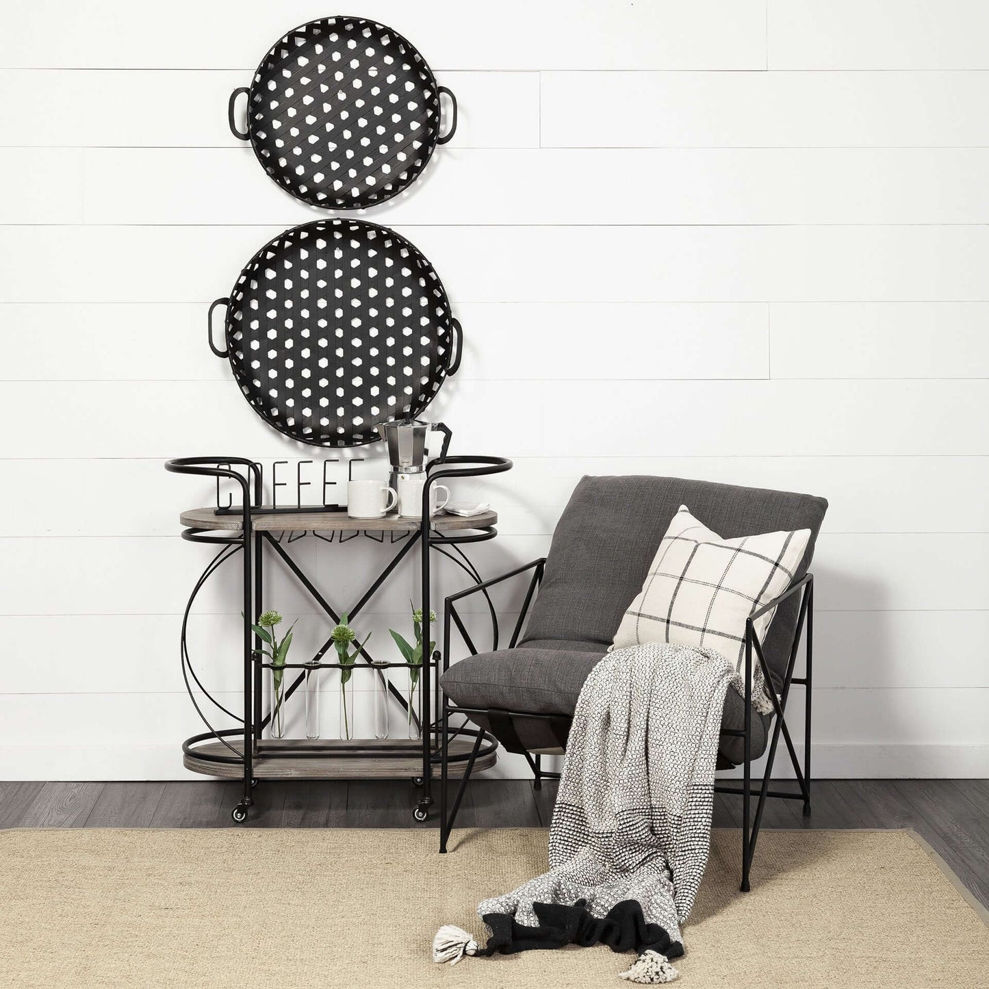 Black Solid Wood and Steel Rolling Kitchen Cart With Storage placed beside a stylish gray chair, featuring round polka-dot trays.