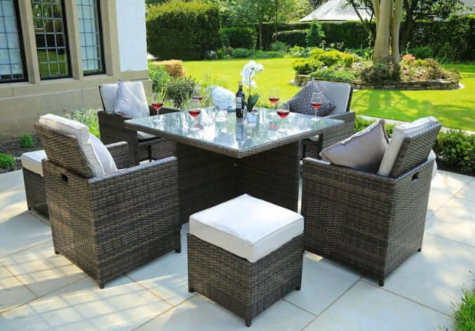 HOMEROOTS Nine Piece Clear and Gray Glass Dining Set displayed outdoors with comfortable seating and elegant decor.