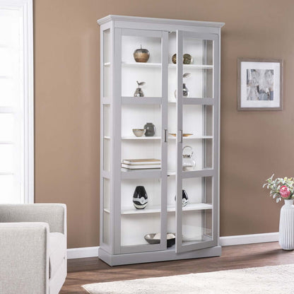 Gray double door curio cabinet with glass shelves showcasing decorative items in a modern living room.