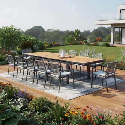 HOMEROOTS 13 Piece Natural and Black Solid Wood Dining Set in a beautiful outdoor setting with flowers and greenery.